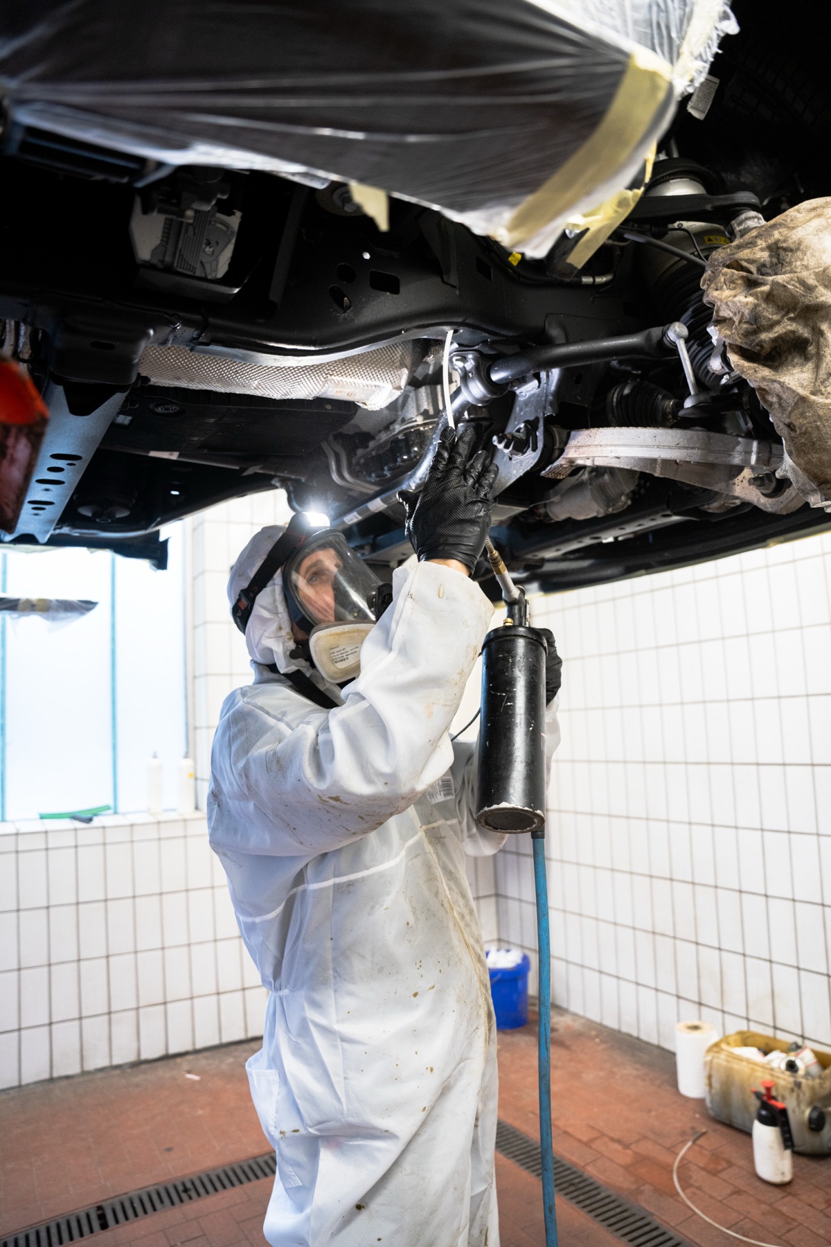 Konservierung – Mitarbeiter trägt Unterbodenschutz auf